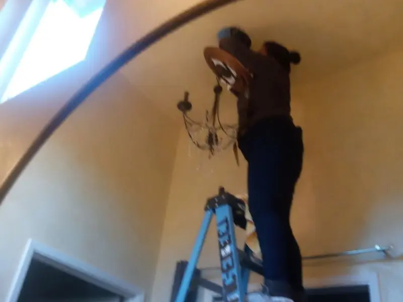 Electrician installing a chandelier in a Rockport residence